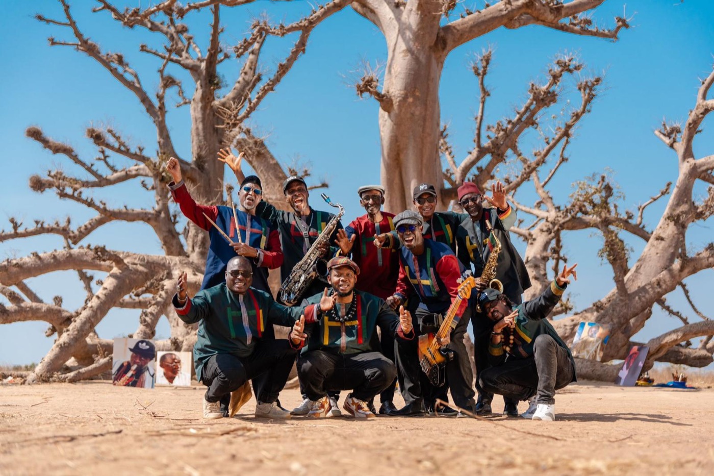 The nine members of Orchestra Baobab gathered beneath a baobab tree in Senegal, instruments in hand.